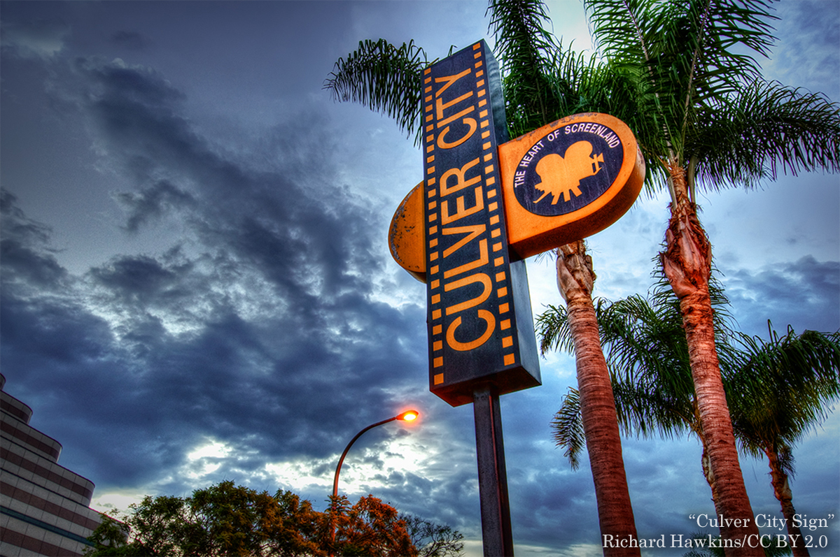 Culver City sign in front of palm tree with sky and clouds in the background